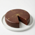 A Sacher Torte with a slice taken out on a white plate against a white background