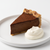 slice of chocolate tart won white plate with scoop of whipped cream