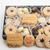 A gift box of assorted holiday cookies on a white background, including star-shaped linzer cookies, chocolate-dipped cookies, and cookies embossed with 'HAPPY HOLIDAYS'.