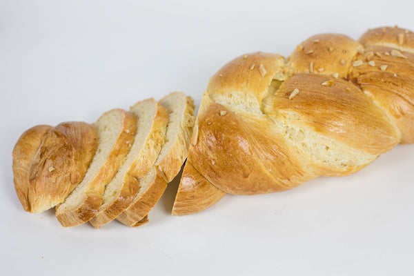 A traditional Austrian Easter bread with almonds sprinkled on top, sliced  on a white background.